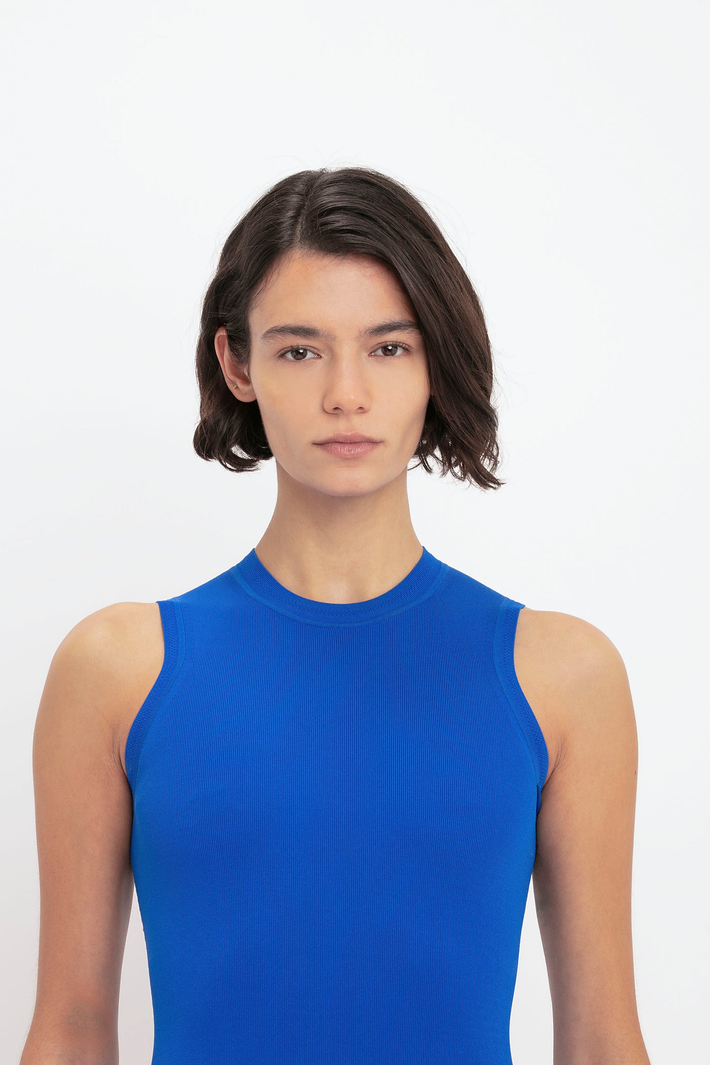 A person with short dark hair wearing a VB Body Mini Dress in Cobalt by Victoria Beckham is looking directly at the camera against a white background.