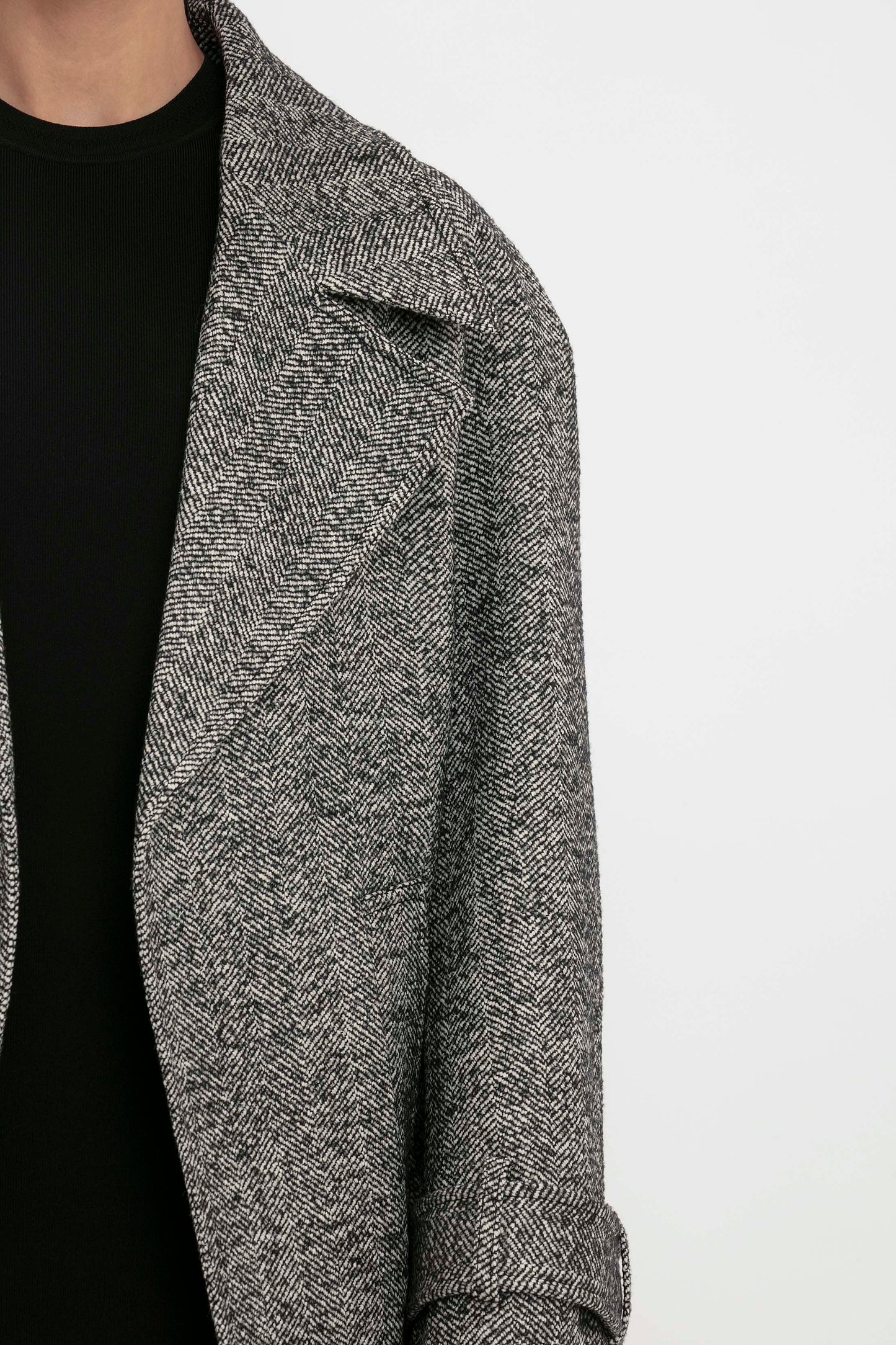 Close-up of a person wearing the VB Body Mini Dress in Black by Victoria Beckham. The image reveals the dress's sleek fabric and neckline details, stopping at the person's shoulder.