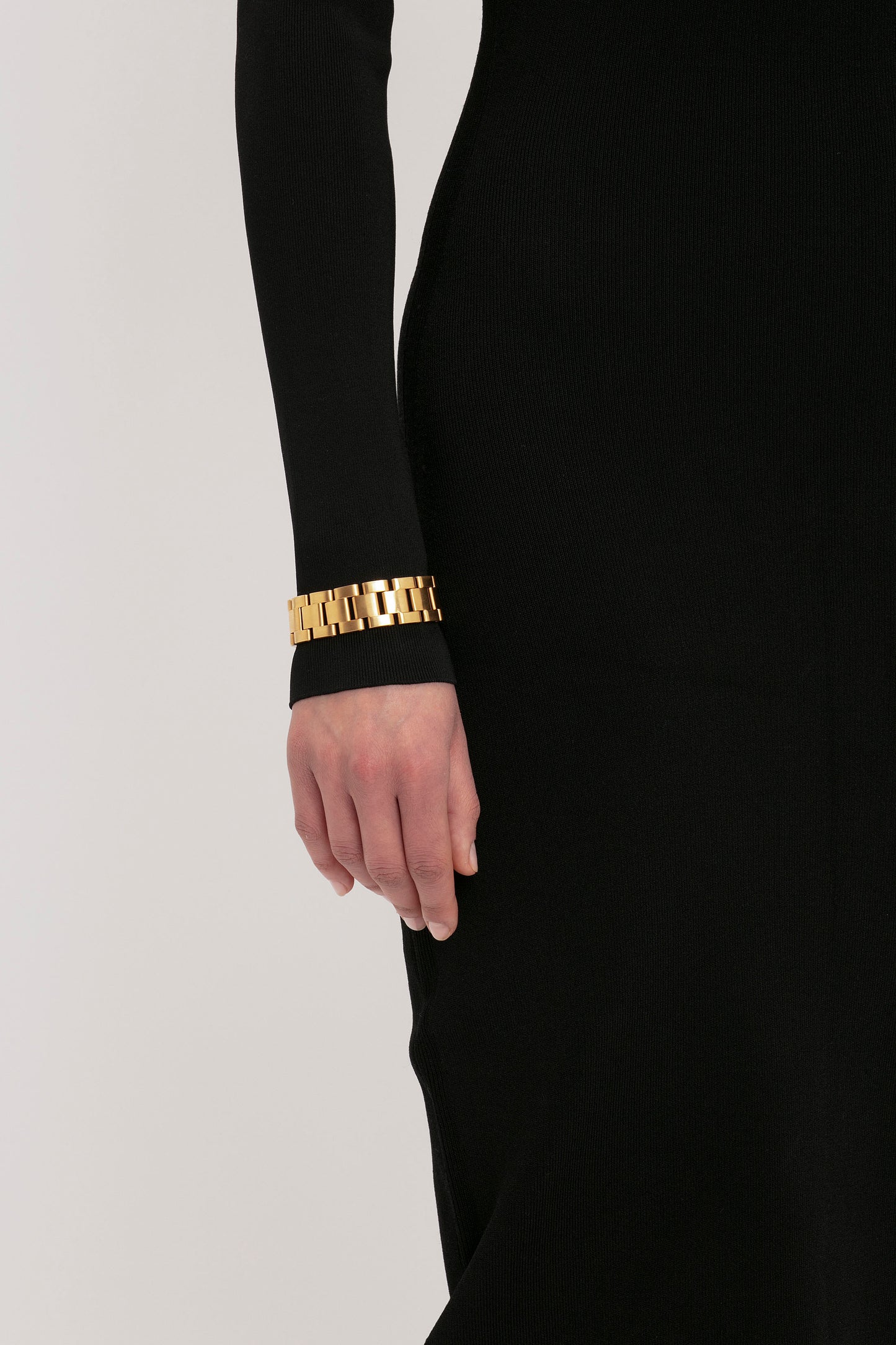 A person wearing the VB Body One Shoulder Top in Black by Victoria Beckham has a gold bracelet on their wrist.