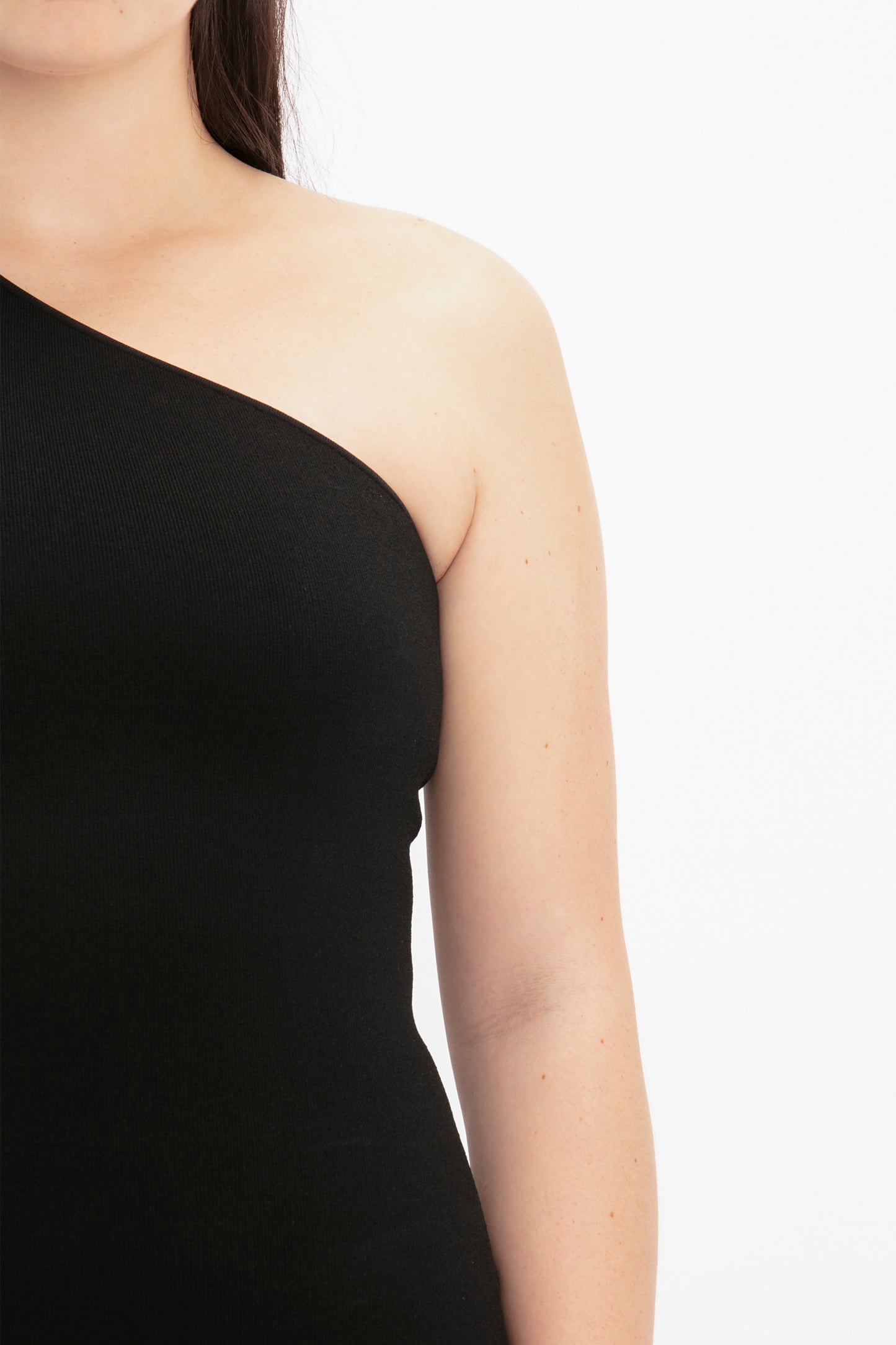 A person wearing the Victoria Beckham VB Body One Shoulder Top in Black against a white background, shown from the neck to just above the elbow.