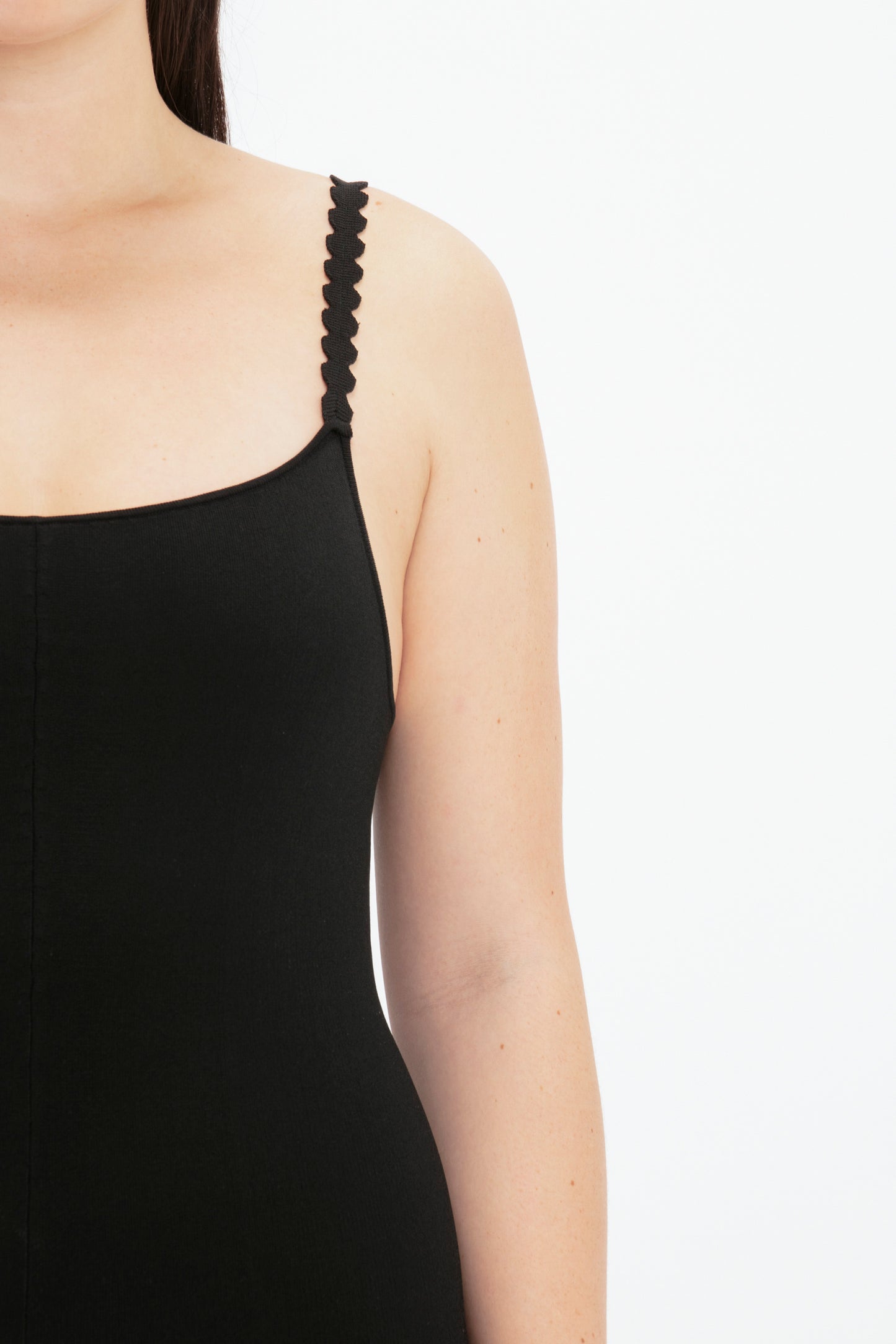 A person wearing the VB Body Catsuit in Black from Victoria Beckham, showing their shoulder and upper arm against a plain white background.