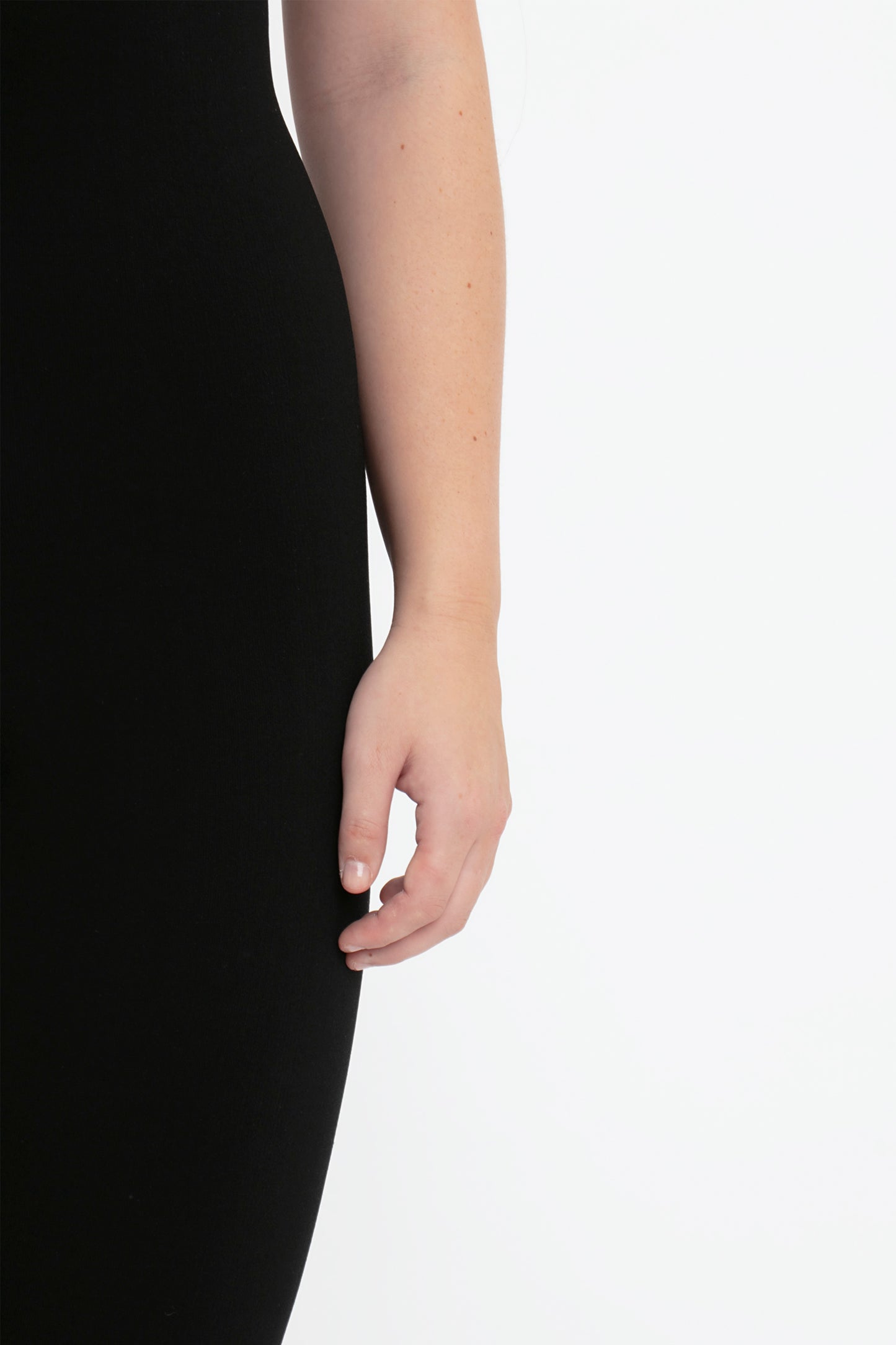 A person's right arm and hand, dressed in the VB Body Catsuit in Black by Victoria Beckham, are visible against a white background.