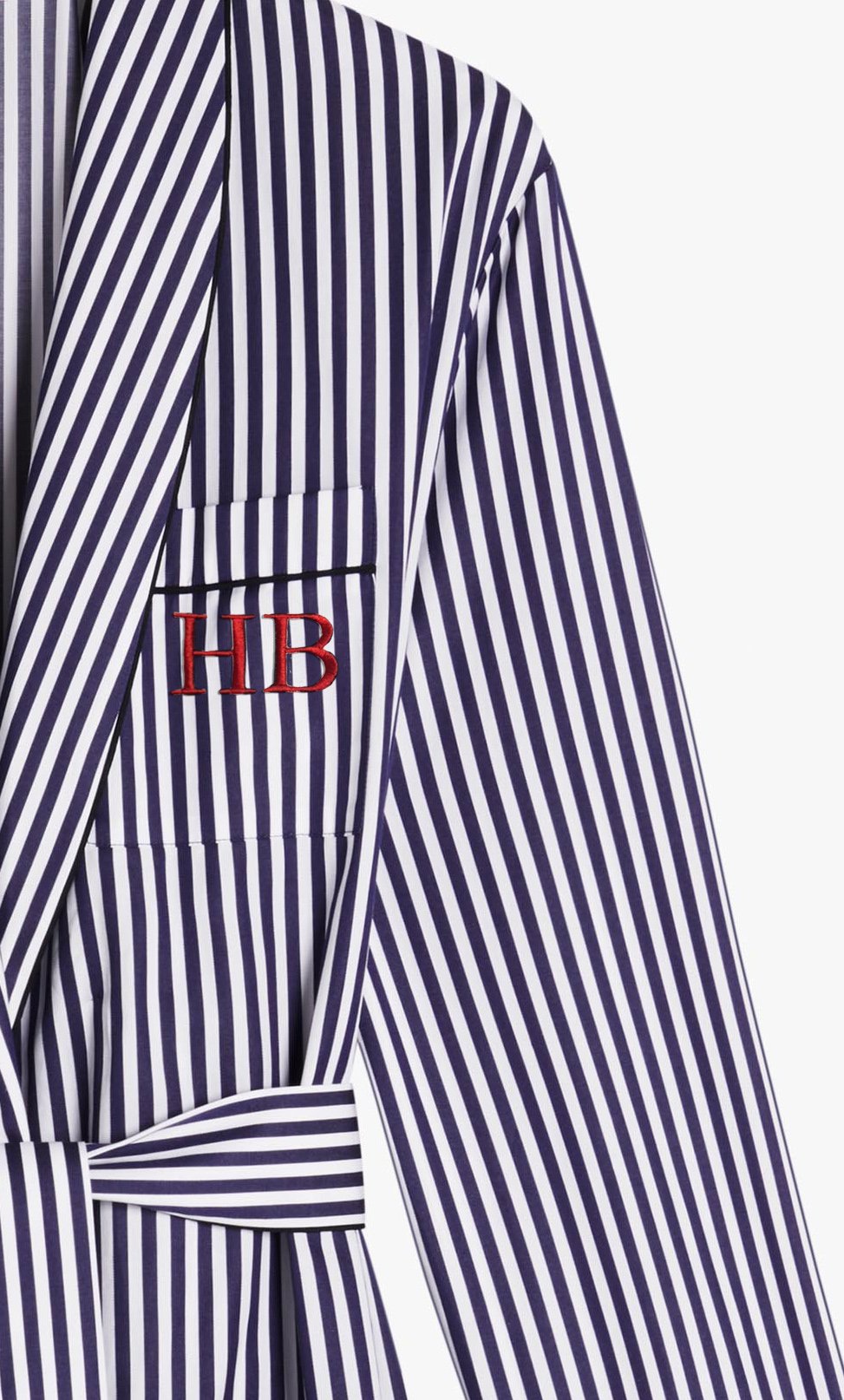 Close-up of a black and white vertically striped garment featuring a red "HB" monogram on the chest pocket by Victoria Beckham, exemplifying exquisite personalisation.