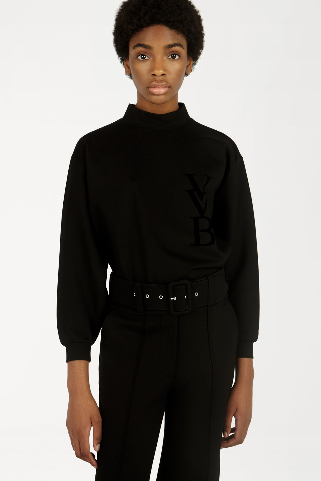 A woman wearing a Victoria Beckham 3D Logo Sweatshirt in Black and pants.