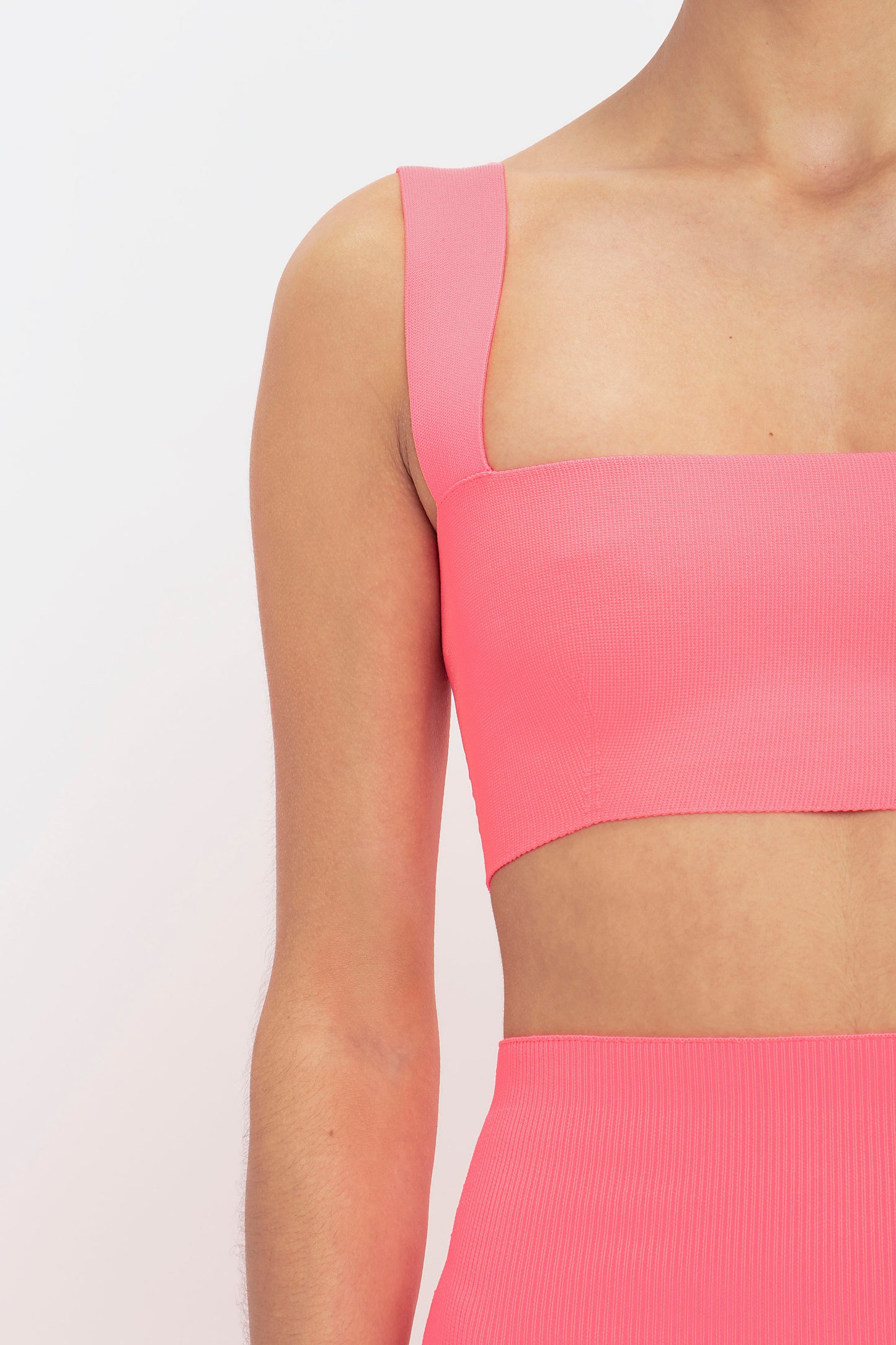 A person wearing the Victoria Beckham VB Body Strap Bandeau Top in Pink and matching high-waisted bottoms, shown from the shoulders to the midriff.