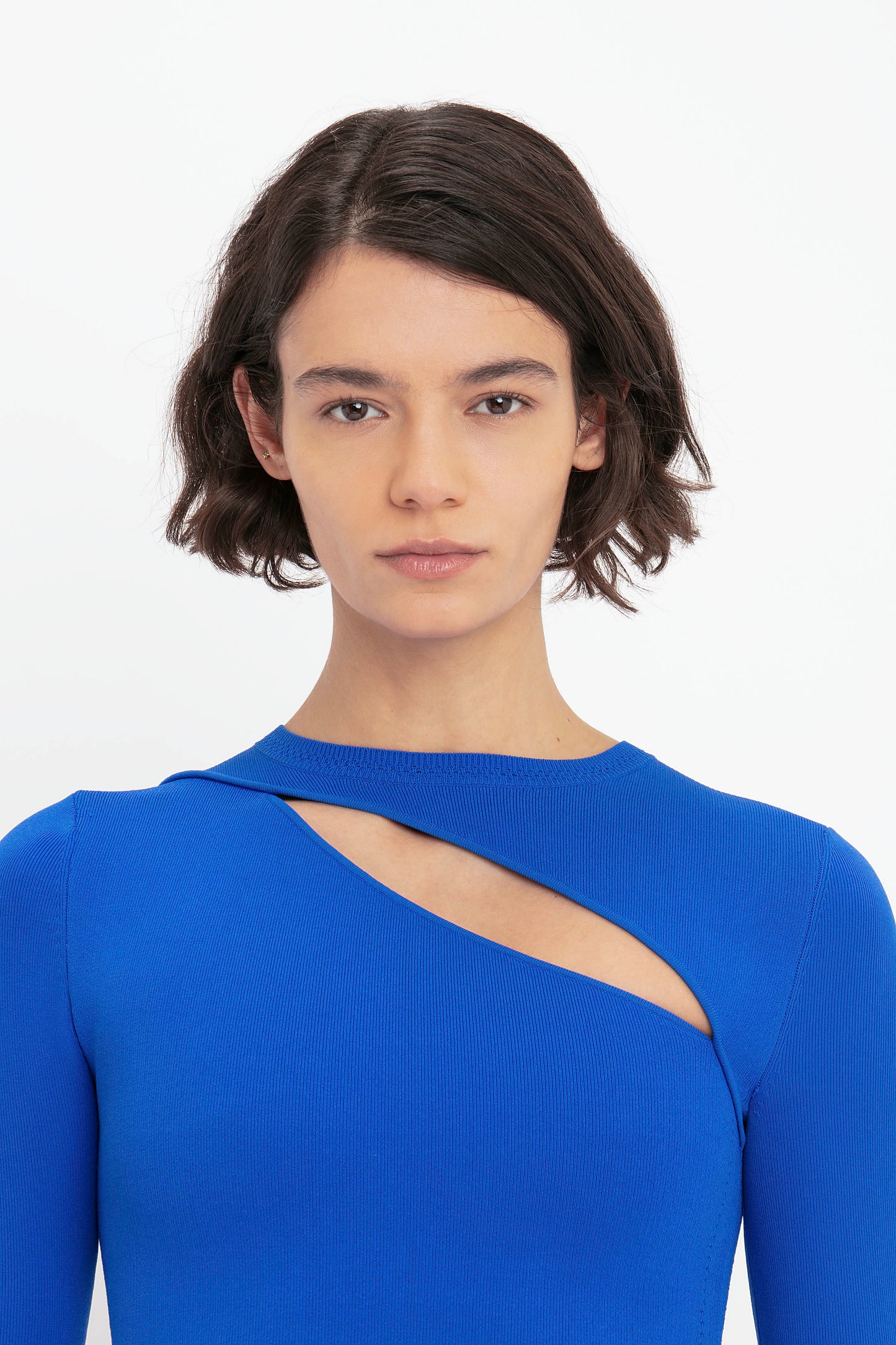 Person with short brown hair wearing the Victoria Beckham VB Body Front Slash Crew Neck Top in Cobalt, looking directly at the camera.