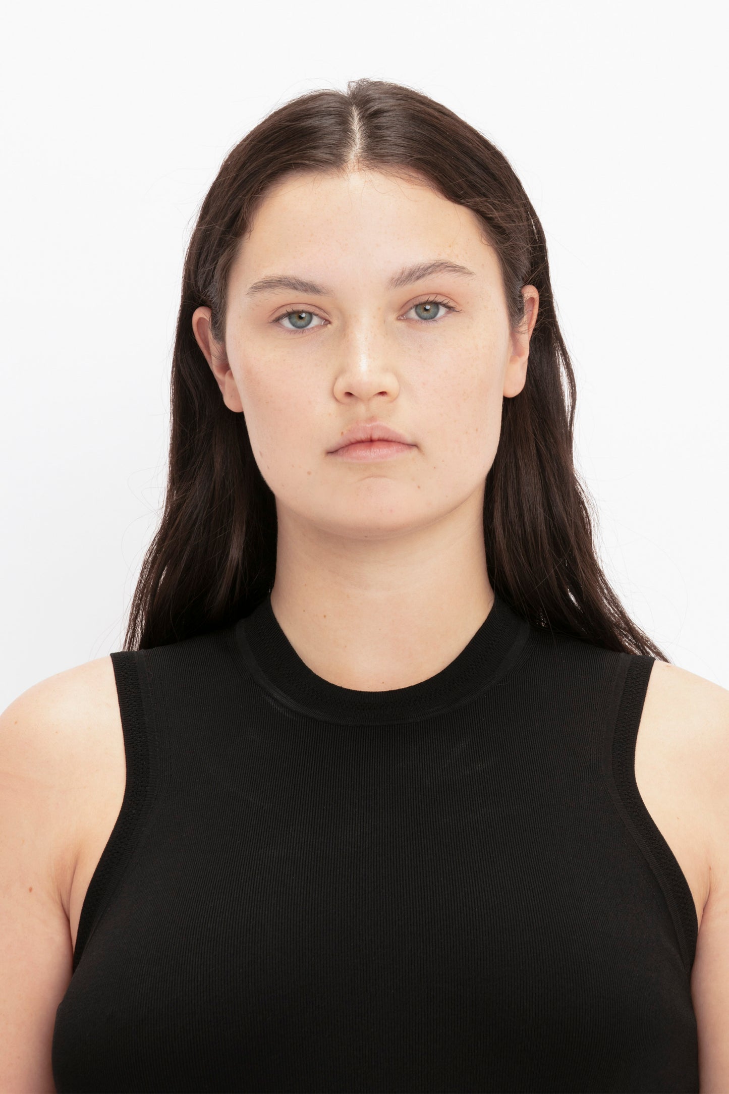 A person with long dark hair, wearing the VB Body Mini Dress in Black by Victoria Beckham, looking directly at the camera against a plain white background.