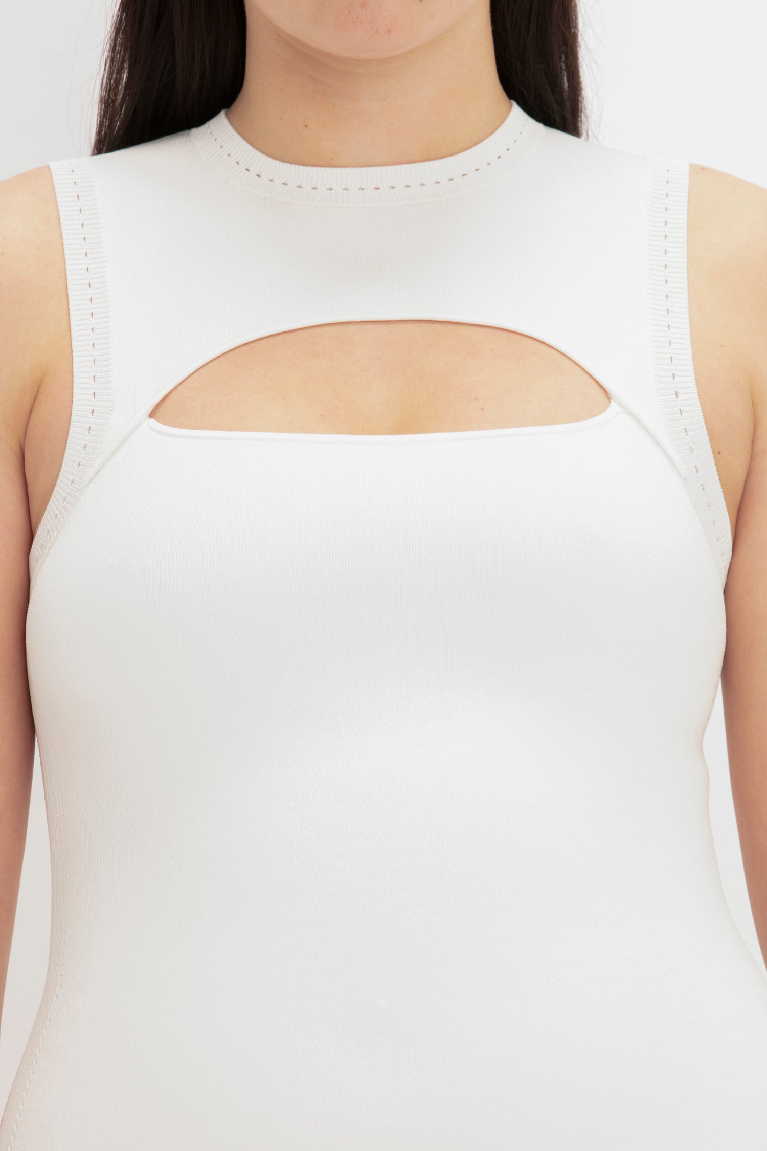 A person wearing the VB Body Slash Front Midi Dress in White by Victoria Beckham, featuring a rectangular cutout across the chest area.