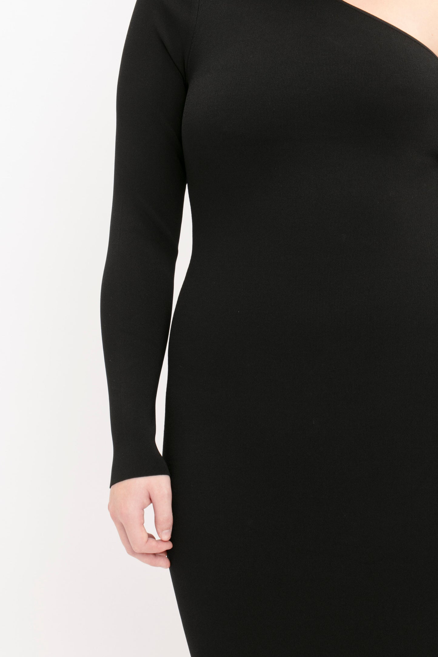 A person wearing the VB Body One Shoulder Midi Dress in Black by Victoria Beckham, which features long sleeves and a cut cropped at the shoulder and knees, stands against a plain white background.
