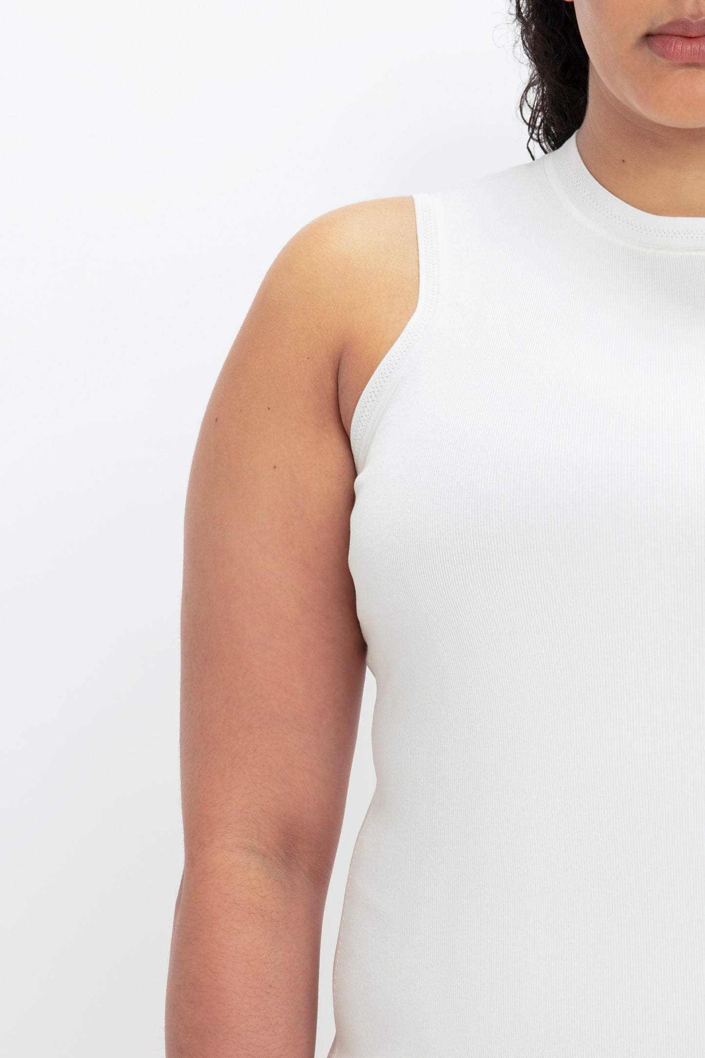 A person wearing a VB Body Mini Dress in White by Victoria Beckham is shown from the shoulder to mid-torso, facing partially forward against a plain white background.