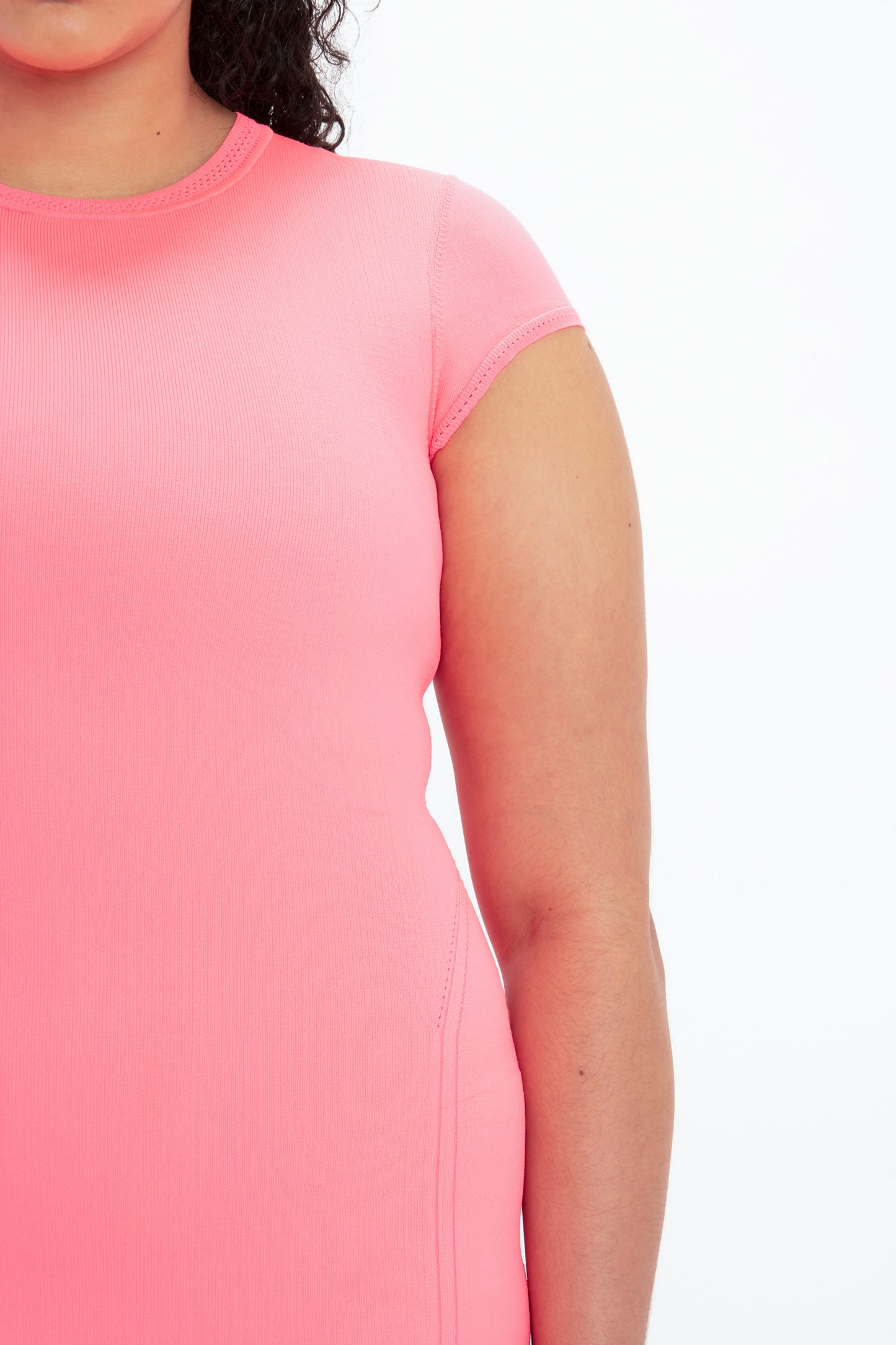 Close-up of a person wearing a Victoria Beckham VB Body Compact Cap Sleeve Mini Dress in Pink, showing the upper body from the shoulder to the mid-torso against a white background.
