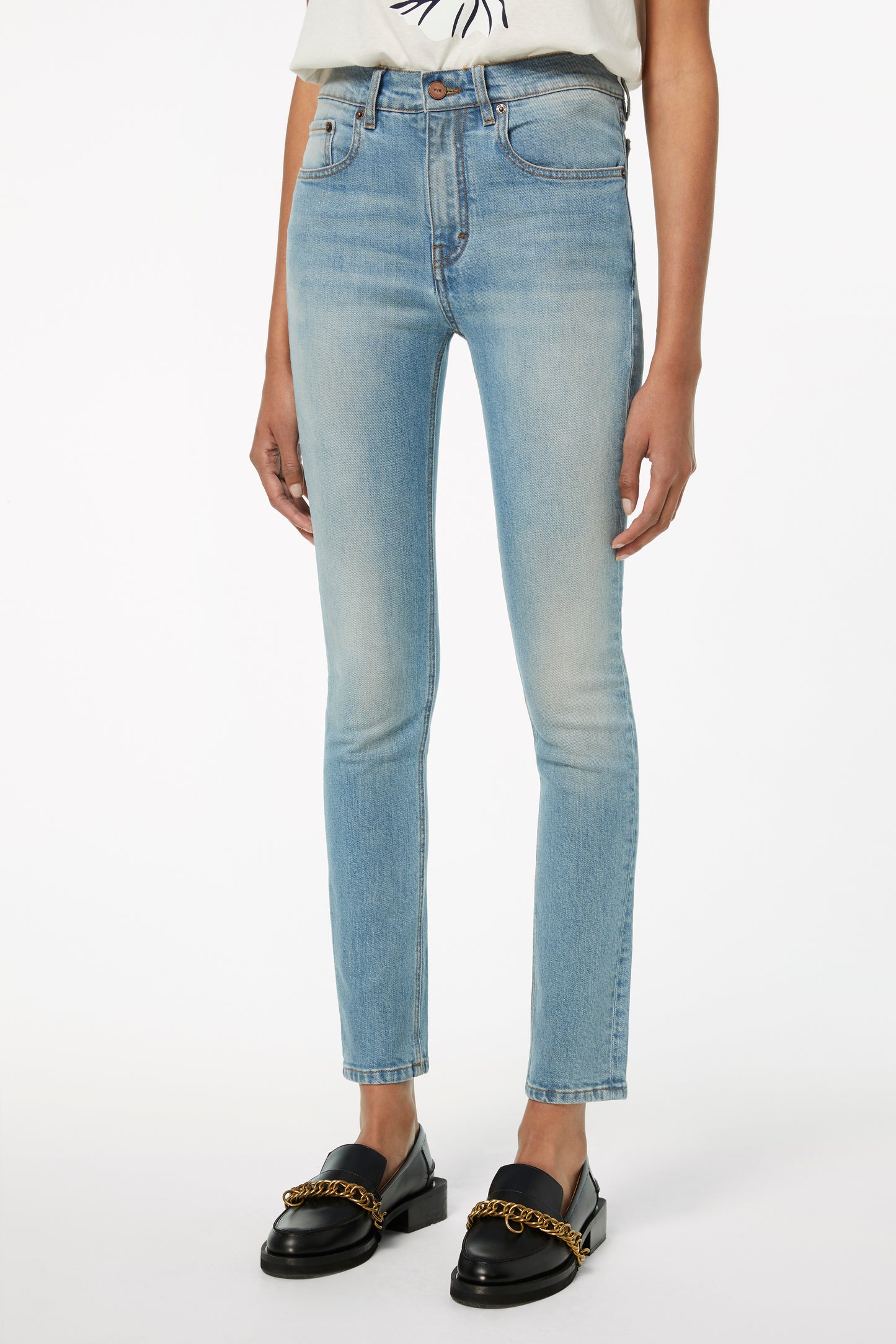 Person wearing Victoria Beckham's Cali Jeans in Parisian Blue, a white T-shirt, and black loafers with gold chain detailing.