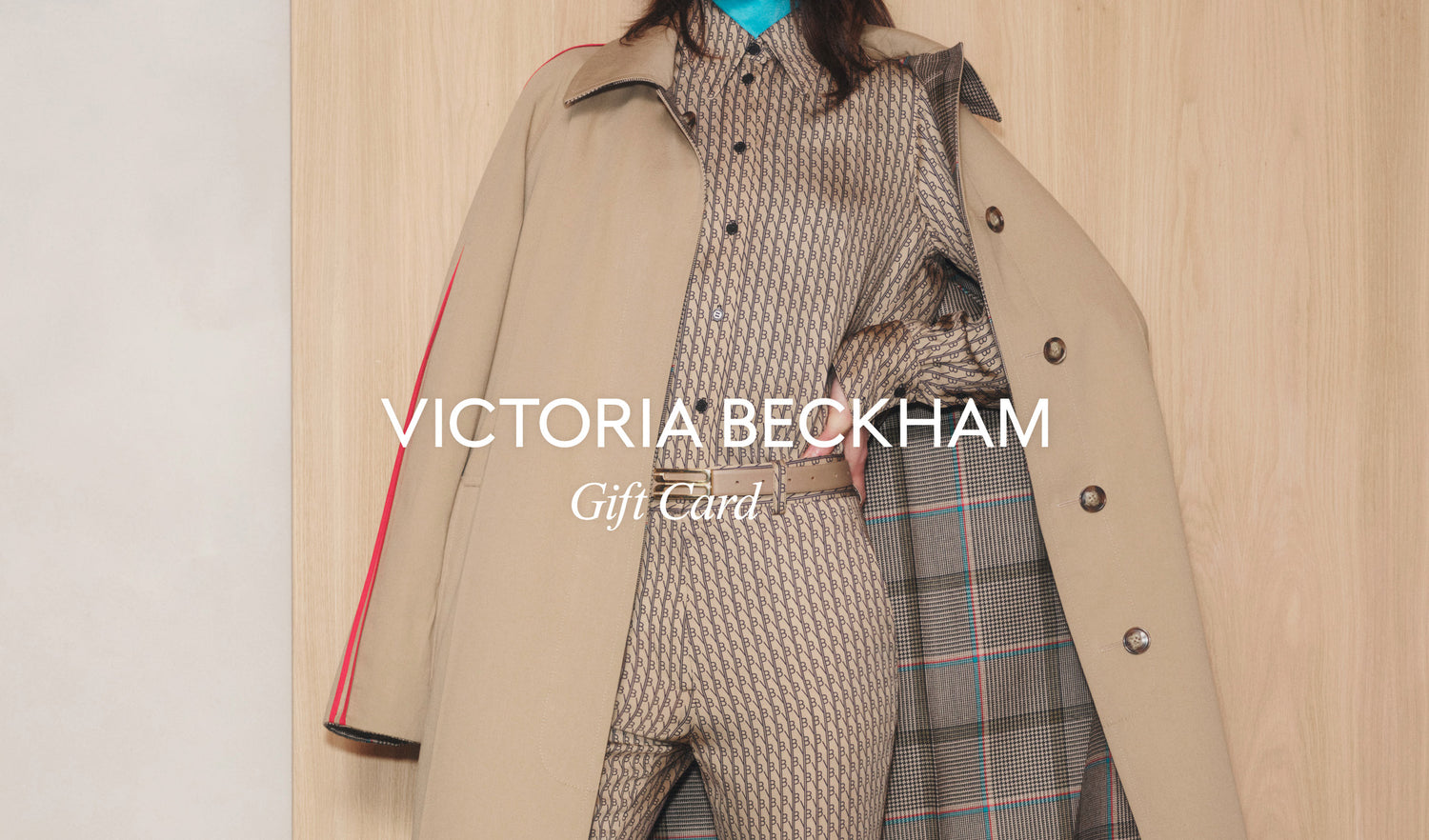 Image of a person wearing a beige patterned suit, partially covered by a beige coat. The text reads "Victoria Beckham VB Gift Card," perfect for that last-minute present with convenient email delivery.