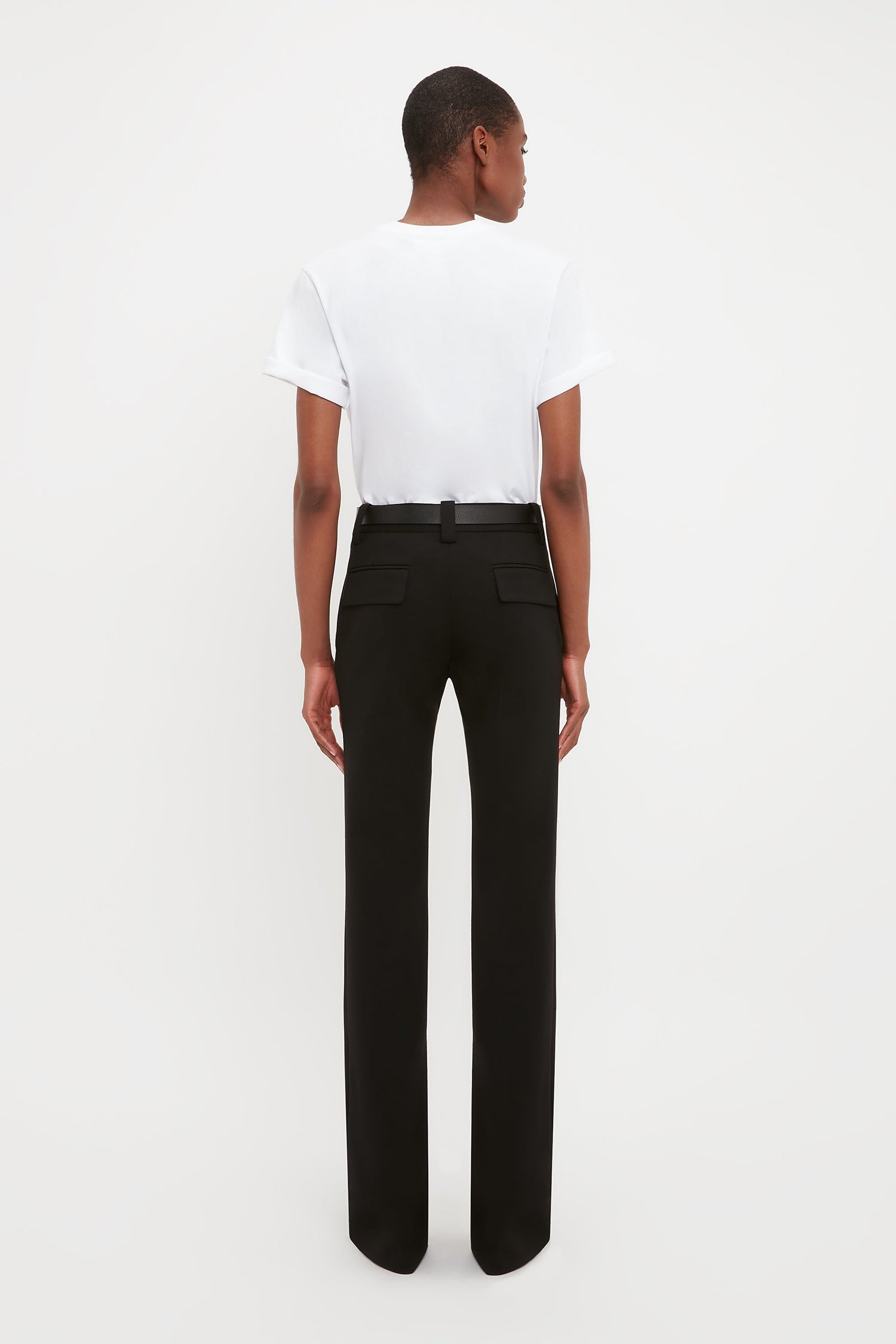 A person faces away, wearing a plain white t-shirt and Victoria Beckham's Tailored Straight Leg Trouser in Black, set against a plain white background.
