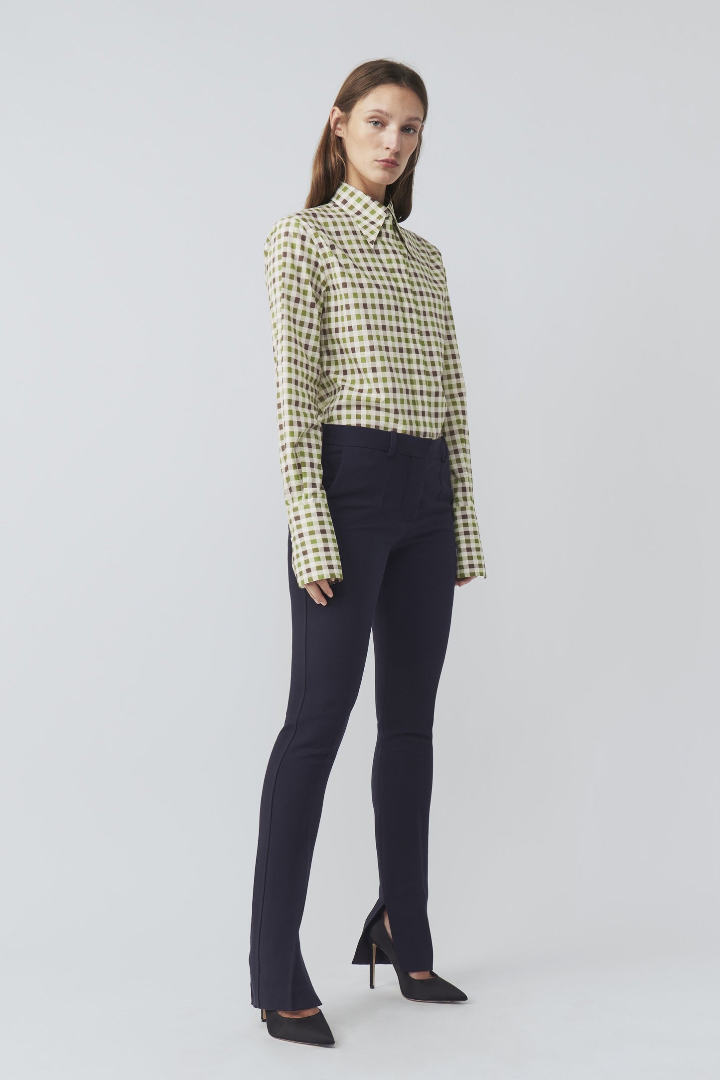 The model is wearing a Victoria Beckham 70's Collar Shirt with a point collar and black pants.