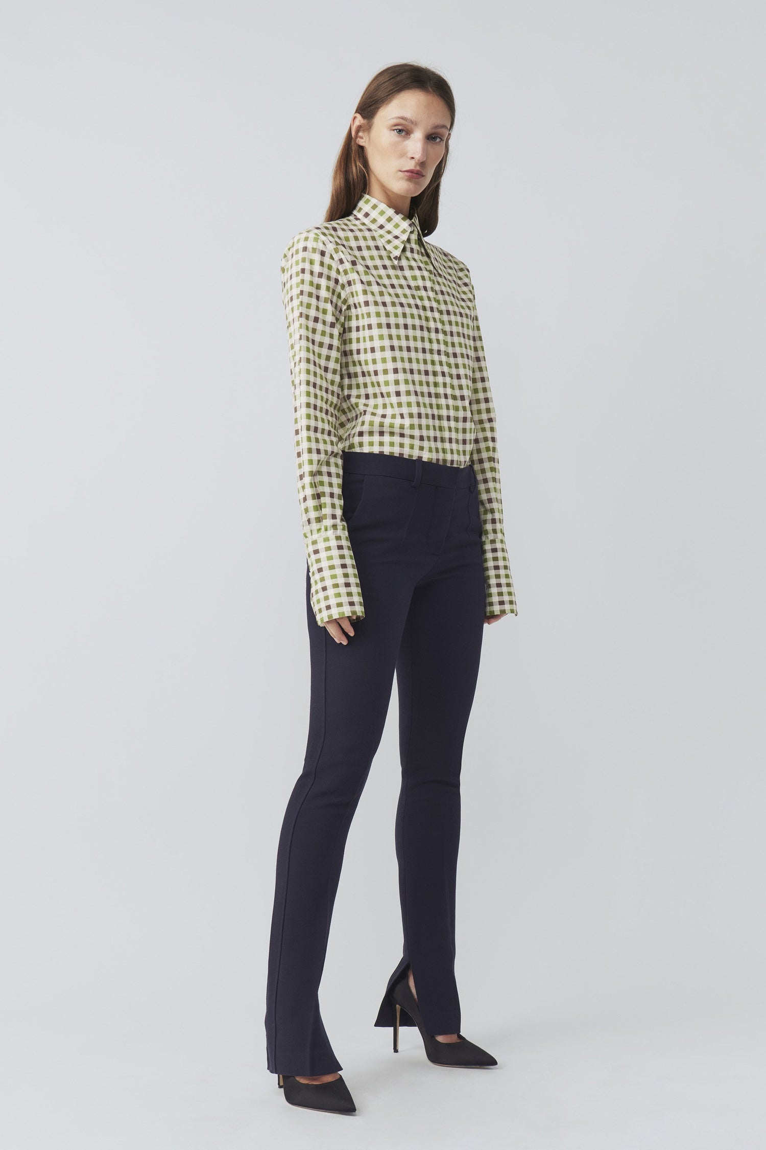 The model is wearing a Victoria Beckham 70's Collar Shirt with a point collar and black pants.