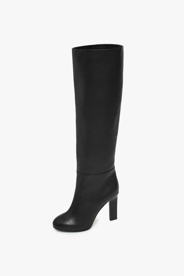 The Victoria Beckham Heel Boot is a black, knee-high boot with a high block heel, expertly handcrafted in Italy, set against a plain white background.