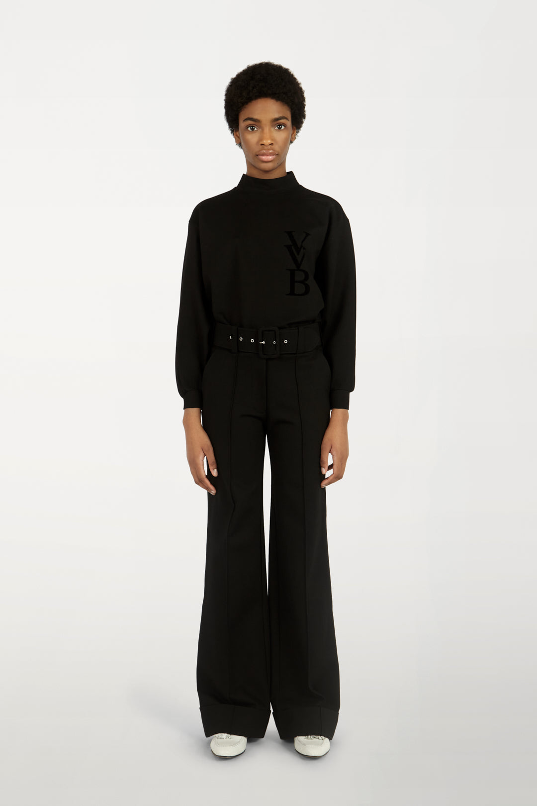 A woman wearing a Victoria Beckham 3D Logo Sweatshirt in Black and wide leg pants.