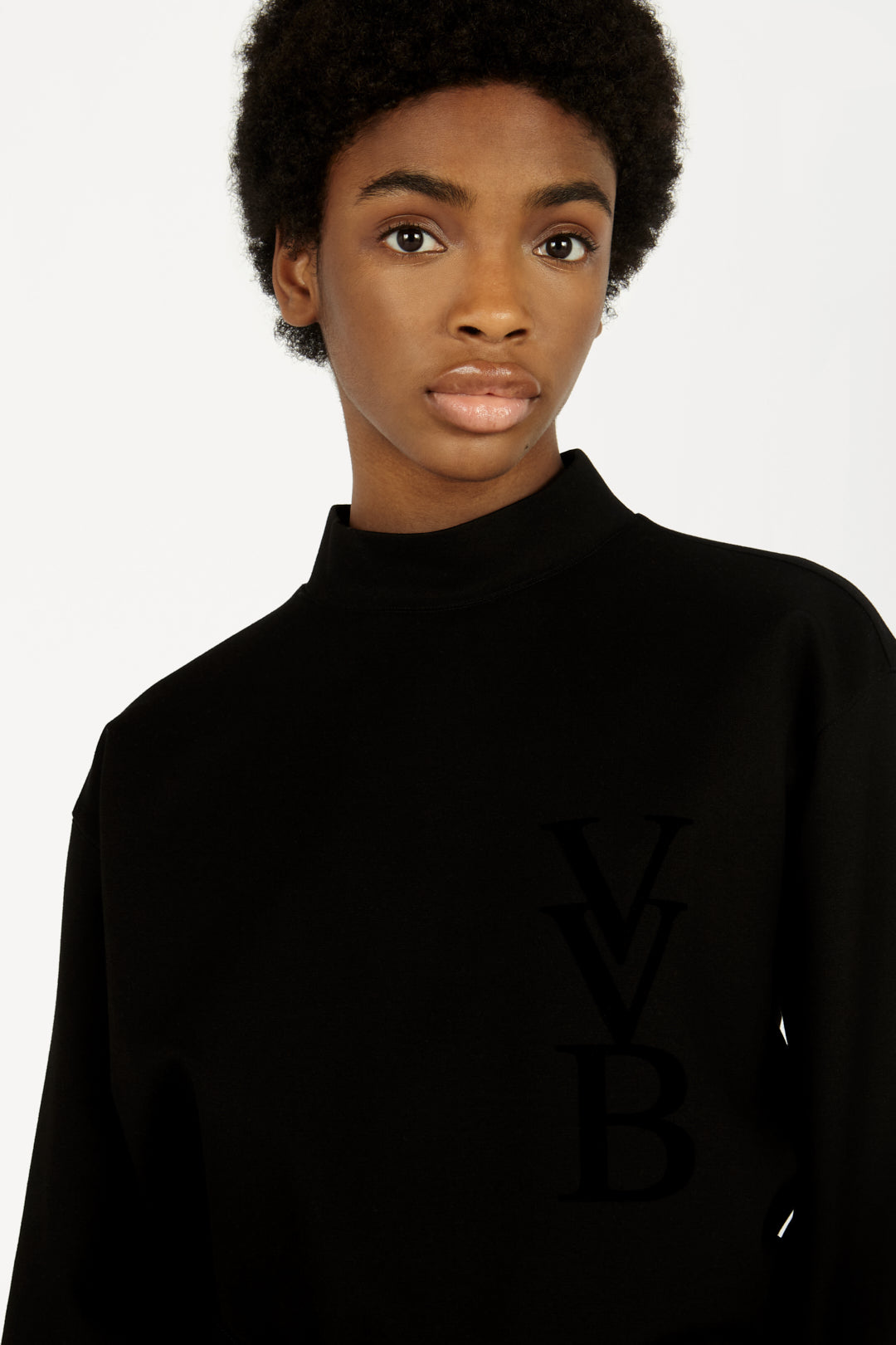 A woman wearing a black loungewear jumper with the word "Victoria Beckham" on it.