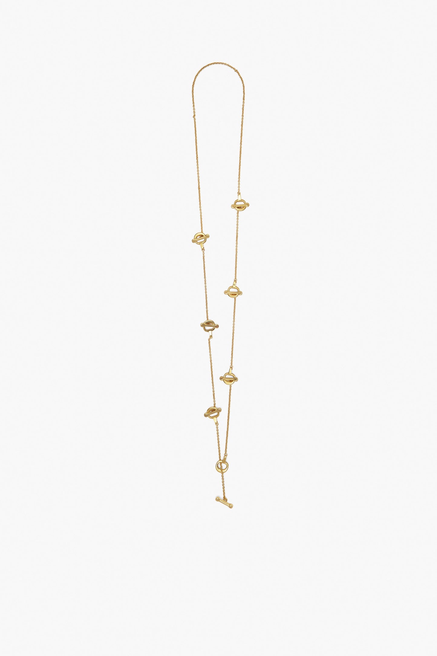 The Victoria Beckham Bridle Necklace in Gold is a handcrafted piece featuring multiple small knot designs, equestrian bridle charms, and a sleek toggle clasp.