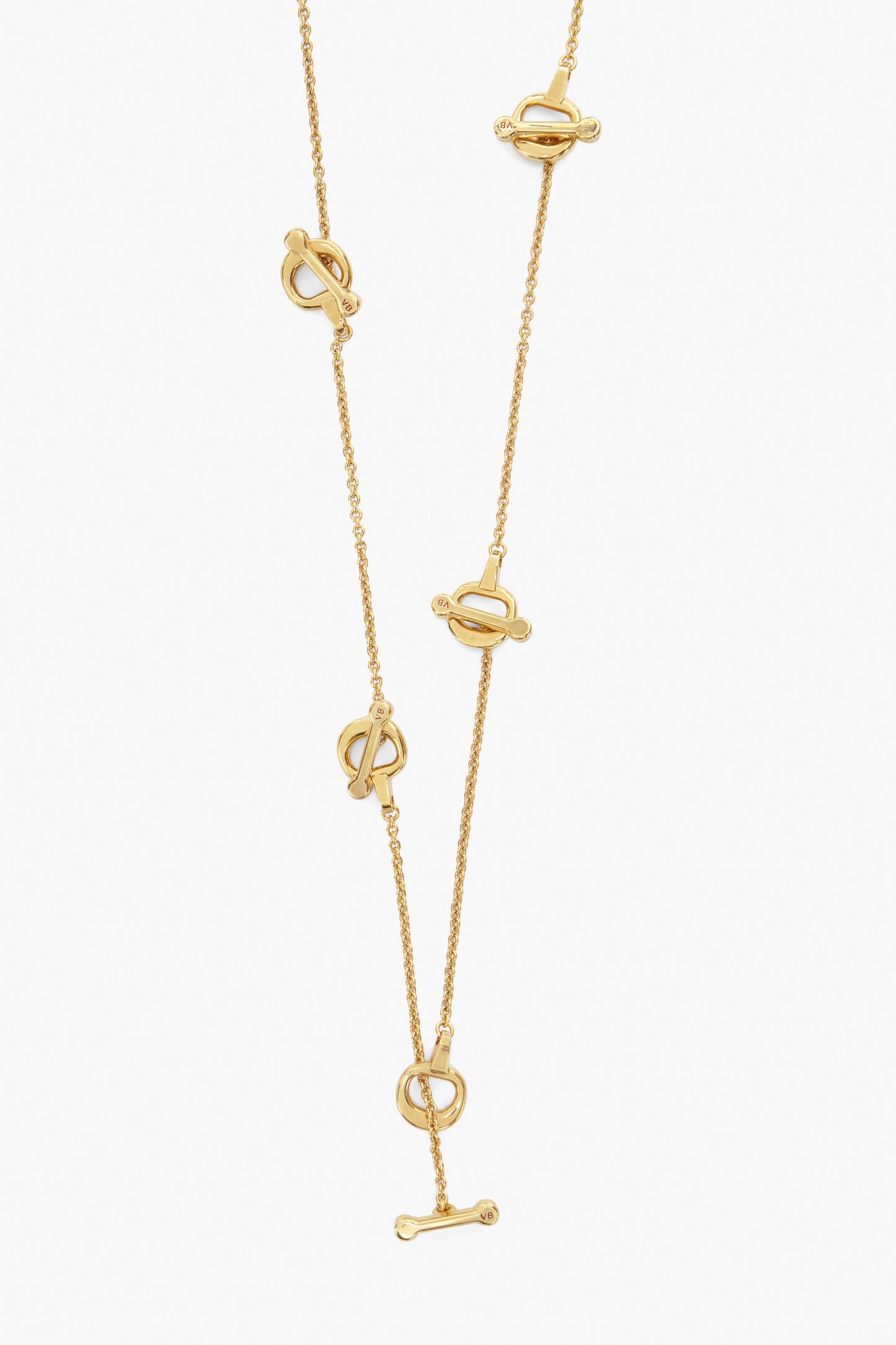 The Victoria Beckham Bridle Necklace in Gold is a handcrafted piece featuring elegant bar and circle toggle closures with unique equestrian bridle charms delicately arranged at intervals.